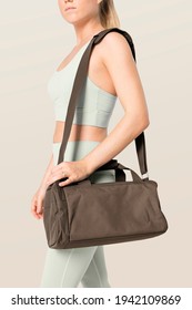 Sporty woman carrying brown duffle bag gym essentials studio shoot