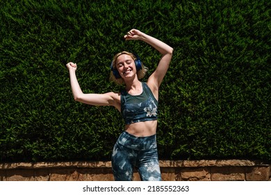 sporty woman dances while listening to music with wireless headphones - Powered by Shutterstock