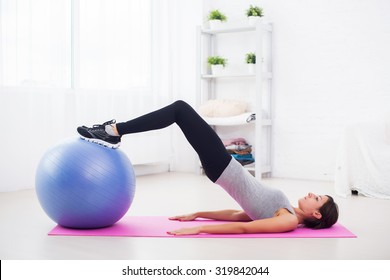 Sporty Woman Doing Pilates Exercise Lifting Her Pelvis With Fit Ball At Home