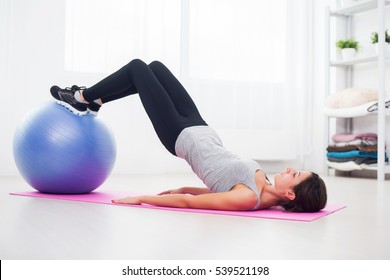 Sporty Woman Doing Pilates Exercise Lifting Her Pelvis With Fit Ball At Home.