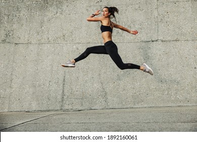 Sporty Woman Doing Running And Jumping Exercise Outdoors. Fitness Female Athlete Exercising Outdoors.