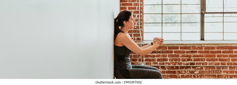 Sporty Woman Doing Squats Against A Wall