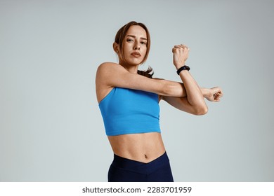 Sporty woman doing warm-up before training session in gym on studio background. High quality photo