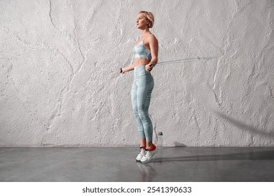 Sporty woman doing workout with jump rope in gym. Female athlete exercising with jumping rope in gym. Young woman with skipping rope in gym. - Powered by Shutterstock