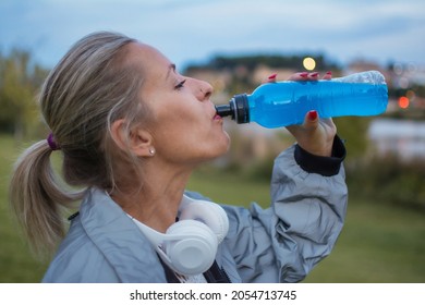 Sporty Woman Drinking Isotonic Beverage.
40 Year Old Blonde Woman Resting And Drinking While Doing Her Daily Exercise Routine In The City