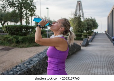 Sporty Woman Drinking Isotonic Beverage. 40 Year Old Blonde Woman Resting And Drinking While Doing Her Daily Exercise Routine In The City