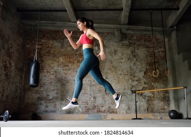 Sporty Woman During HIIT Workout. Dynamic Movement. Sportswoman Jumping High In The Process Of Training In The Gym