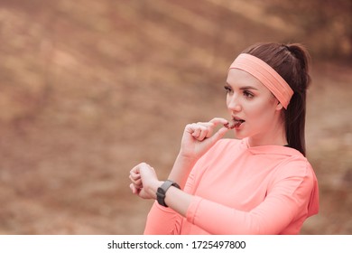 Sporty Woman Eating Energy Bar After Running. Athletic Sporty Woman After Jogging In Park. Beautiful And Fit Woman Checks Achievements After Her Exercise On Smart Watch. Healthy Lifestyle Content.