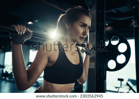 Sporty woman exercising with weight plate in the gym.