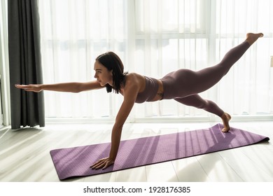 Sporty woman in grey sportswear, bra and leggings practicing yoga, doing Push ups or press ups exercise, phalankasana, variation of Plank pose, beautiful girl working out at home or in yoga studio - Powered by Shutterstock