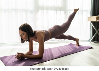 Sporty woman in grey sportswear, bra and leggings practicing yoga, doing Push ups or press ups exercise, phalankasana, variation of Plank pose, beautiful girl working out at home or in yoga studio - Powered by Shutterstock