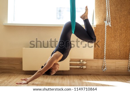 sporty woman is in the inversted yoga position in the sport club