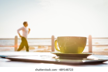 Sporty woman jogging at promenade against cup of coffee and tablet pc - Powered by Shutterstock