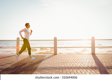 Sporty woman jogging at promenade on a sunny day - Powered by Shutterstock