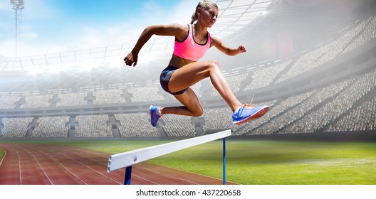 Sporty woman jumping a hurdle against view of a stadium