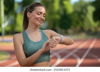 Sporty woman looking at smartwatch on her wrist, tracking fitness activity during training outdoors - Powered by Shutterstock