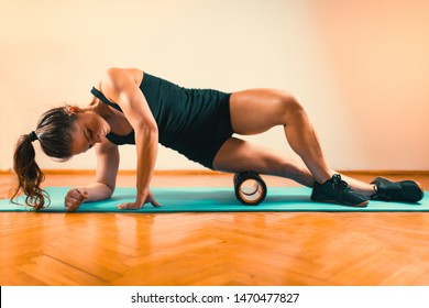 Sporty Woman Massaging Her Legs with Foam Roller 