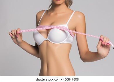 Sporty woman measuring up her chest, isolated in white