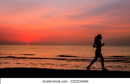 Sporty Woman With Pony Tail Running On The Beach During Sunrise