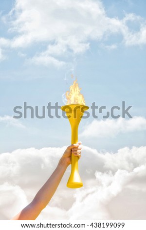Sporty woman posing and smiling with Olympic torch against cloudy sky