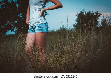 Sporty Woman Posing In The Tall Grass With Bare Legs Wearied In Denim Shorts