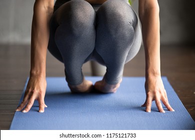 Sporty woman practicing yoga, doing foot strengthening exercise, healing physical therapy pose, working out, wearing sportswear, grey pants, indoor close up, yoga studio