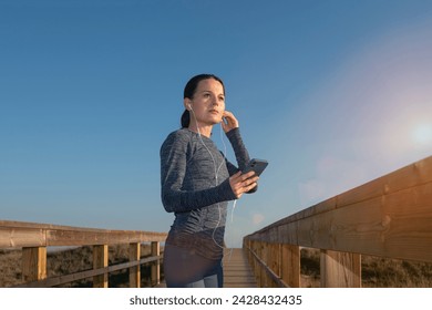 Sporty woman runner adjusting her earphones, preparation listening to music while jogging. - Powered by Shutterstock