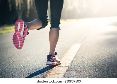 Sporty woman running on road at sunrise. Fitness and workout wellness concept. 
