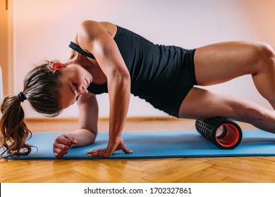 Sporty Woman Self Massaging Legs With Foam Roller At Home