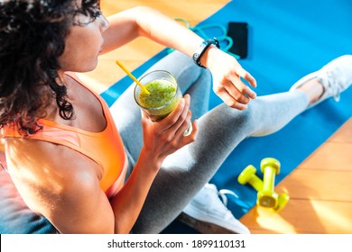 Sporty Woman In Sportswear Training At Home Drinking Fresh Smoothie - Fit Female Athlete Using Smart Watch To Monitor Her Performance - Sport, Food And Technology Concept.