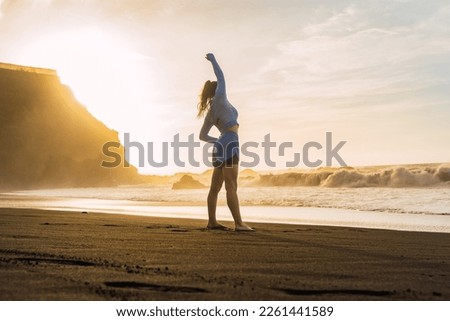 sporty woman stretching her shoulders on the beach.