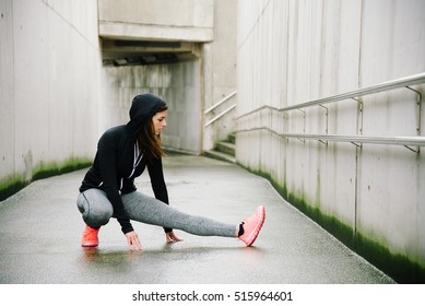 Sporty Woman Stretching And Warming Up Legs For Running Urban Fitness Winter Workout. Sport And Healthy Lifestyle Concept. Female Athlete Exercising Outside.