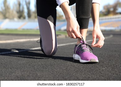 Sporty Woman Tying Shoelaces At Stadium On Sunny Morning, Closeup