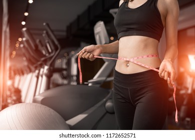 Sporty woman using waist tape line in fitness gym sport club training center near window with condominium background. Lifestyle of people workout exercise sport activity. Diet and weight loss theme.