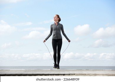 Sporty Woman Warming Up With Jump Rope Outdoors