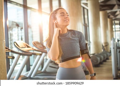 Sporty Woman With Wireless Earbuds Listening To Music At Gym