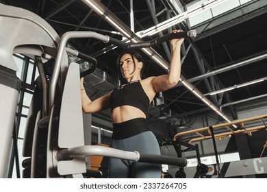 Sporty woman workout pulling up on bar in fitness gym. Lady bodybuilder exercising pulls herself in sports center, weight working out. Healthy lifestyle and sport training concept. Copy ad text space - Powered by Shutterstock