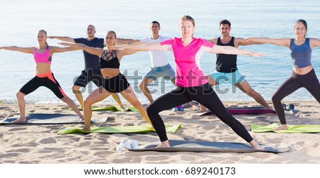 Sporty women and men during training outdoors on sunny beach