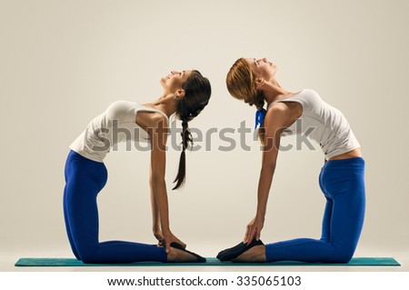 sporty yogi sisters doing fitness training. studio shot. pair, couple yoga