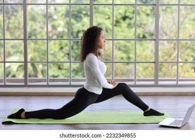 Sporty young adult woman sit on yoga mat practicing mediate yoga watching coach training video online from laptop. Healthy female doing exercise and taking lesson distant course among nature outdoor - Shutterstock ID 2232349855