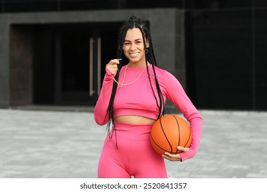 Sporty young African-American trainer with ball for playing basketball and whistle outdoors - Powered by Shutterstock