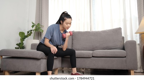 Sporty young asian woman doing exercising with dumbbells and watching fitness video tutorial online on laptop in the living room, Sport at home training, online fitness class, Healthy lifestyle. - Shutterstock ID 1784944721
