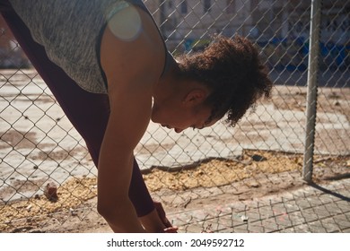 Sporty Young Black Woman Tying Her Shoe Laces While Exercising Alone Outdoors In The Morning