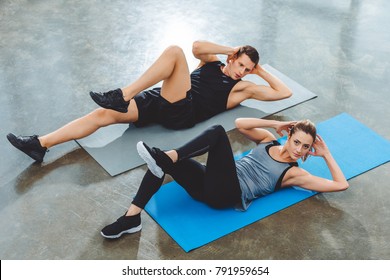 Sporty Young Couple Doing Abs Exercise In Gym