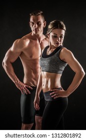Sportliches, junges Paar mit Hantel auf schwarzem Hintergrund