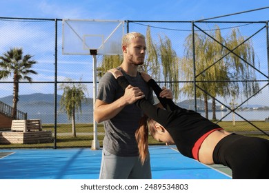 Sporty young couple working out on a basketball court outdoors. Couple goals concept. Boyfriend and girlfriend stretching in the park. Copy space, background. - Powered by Shutterstock