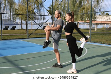 Sporty young couple working out on a basketball court outdoors. Couple goals concept. Boyfriend and girlfriend stretching in the park. Copy space, background. - Powered by Shutterstock