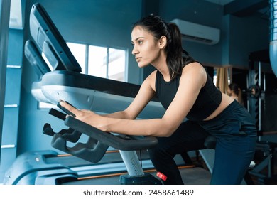 Sporty Young fit indian adult girl do Cardio exercise  cycling at gym. Sport woman workout, Fitness healthy lifestyle concept. Motivation, Determination, Slim body. Burn calories and fat, Challenge - Powered by Shutterstock