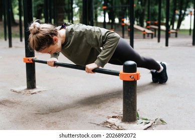 Sporty young fit woman in sportswear exercising on playground doing physical strength exercise, bar push-ups, fitness morning workout outdoors. Healthy active lifestyle concept. - Powered by Shutterstock