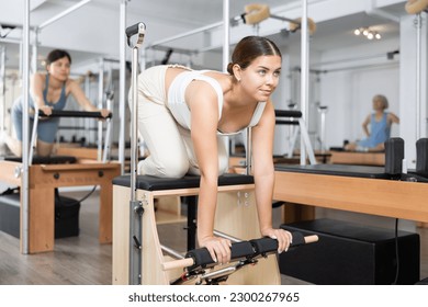 Sporty young girl practicing pilates in fitness studio, doing stretching exercises on wunda chair.. - Powered by Shutterstock